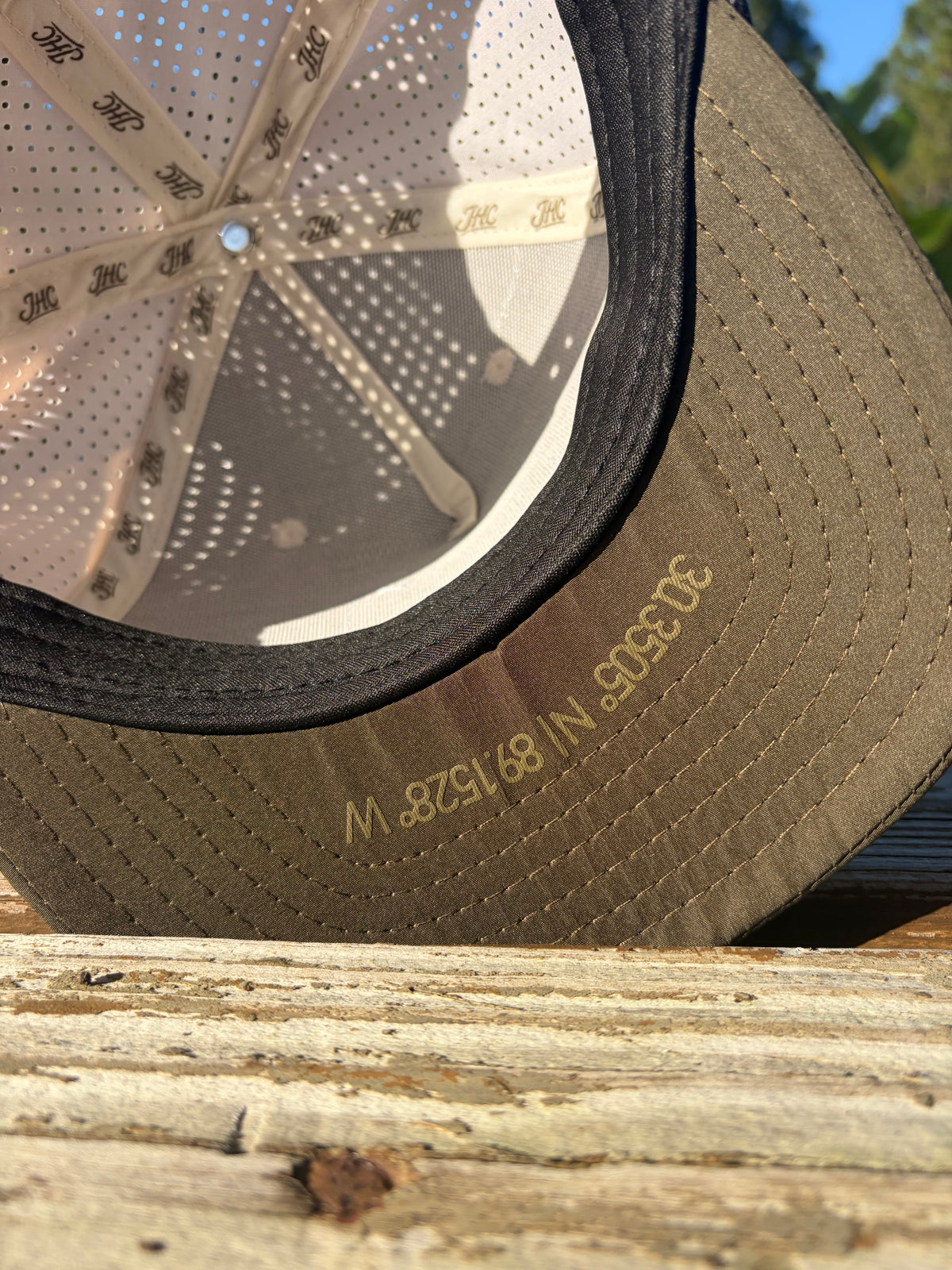 Close-up of latitude and longitude beneath a Jones Hat Co. bill